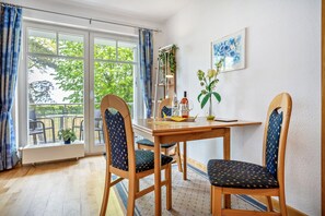 A dining area with a table, chairs, a potted plant, and a window with curtains. - Apartment Blaue Brise for 5 Guests (67 m²) with Lake View in Breege-Juliusruh (Breege)