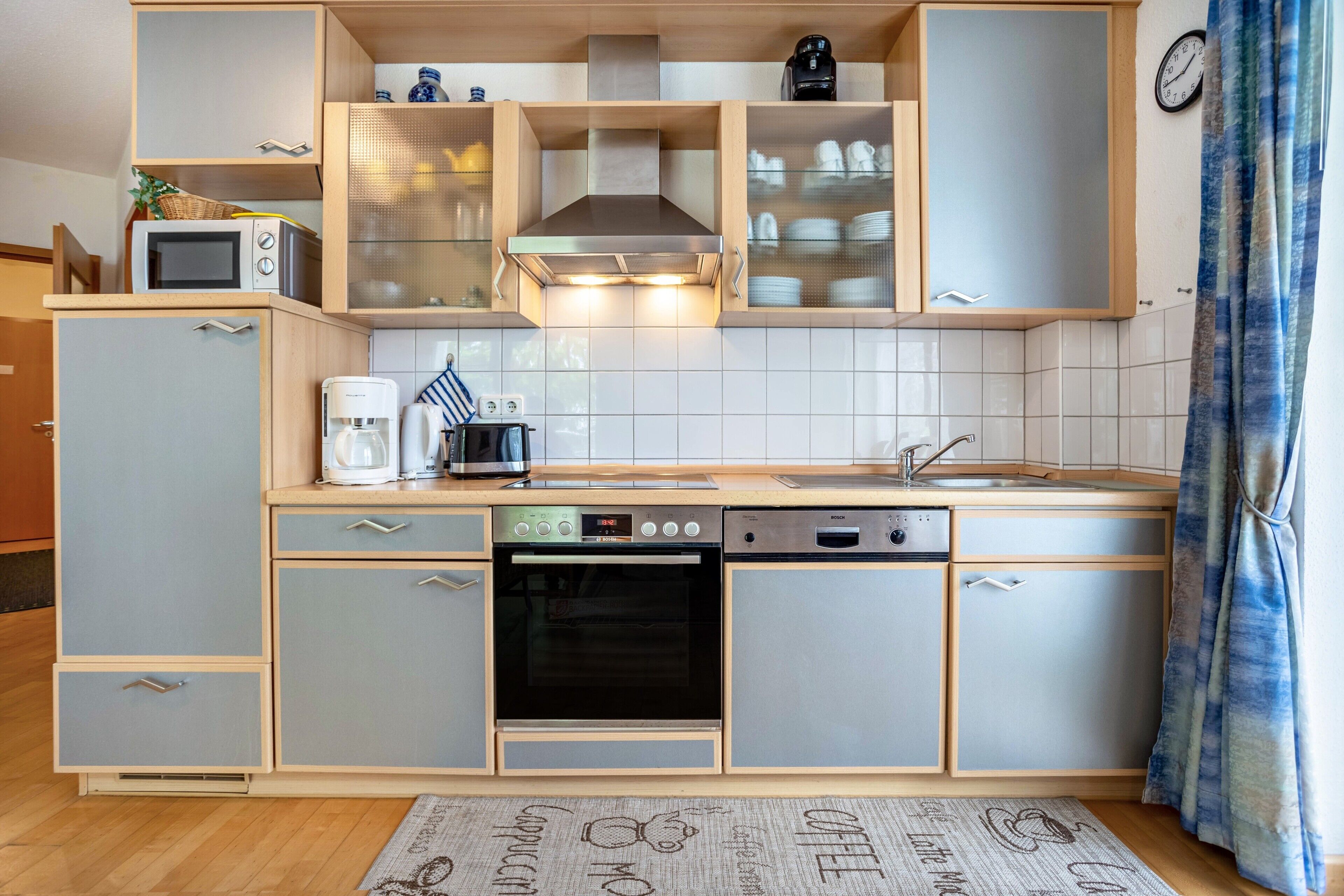 Cocina compacta equipada con microondas, cafetera, horno y lavavajillas.