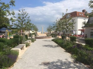 A pathway leading to a central monument surrounded by greenery and buildings. - Pelikan Apartment for 4 Guests (45 m²) in Breege-Juliusruh Seaside Resort (Breege)