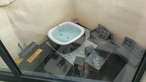 A hot tub in a corner with a glass enclosure, a small table, and a cushioned seating area. - Holiday Home “Vias” with Private Terrace, Wi-Fi and Air Conditioning (Vias)