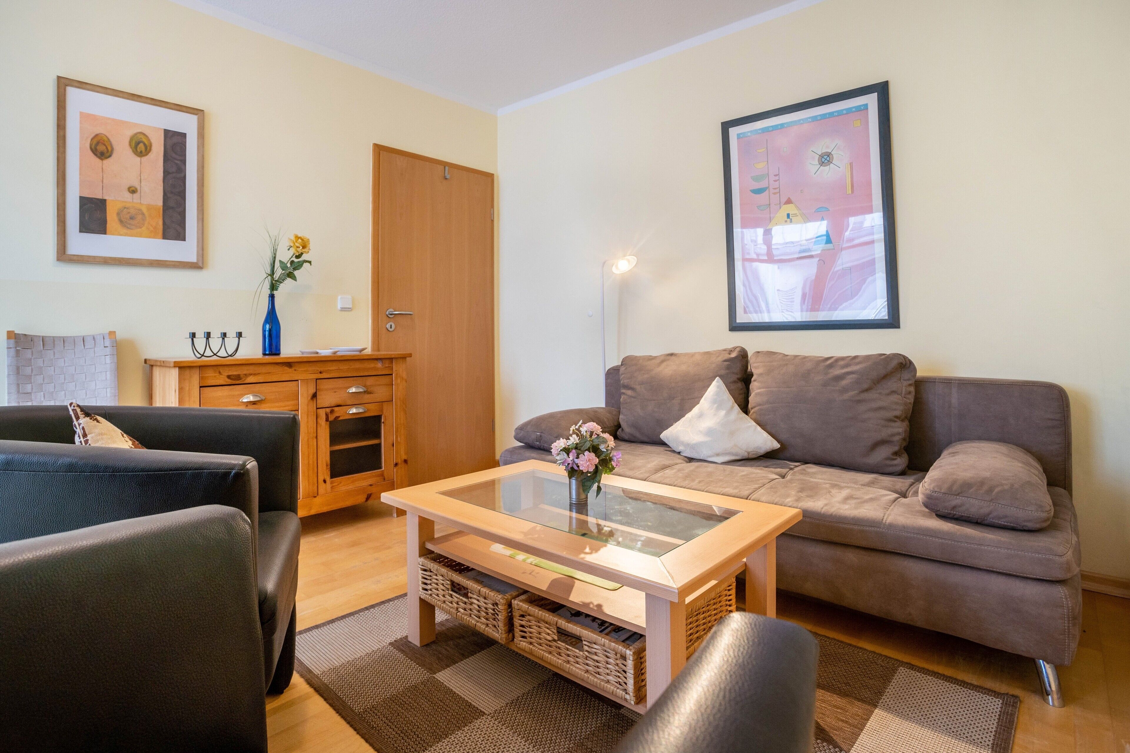 Una sala de estar con sofá, sillones, una mesa de centro y un aparador.