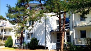 A white multi-story building with balconies, surrounded by trees. - Apartment Seelöwe for 8 Guests, 90 m² Terrace, Beach Chair, Shared Garden in Juliusruh (Breege)