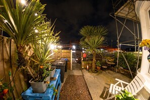 A nighttime outdoor area with potted plants, a blue bench, and white chairs. - Characterful top-floor flat · Fireplace · Steps from Pleasure Beach (Blackpool)