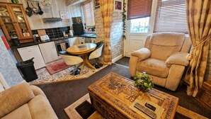 Un espacio habitable compacto con kitchenette, zona de comedor, sofá y una mesa de centro decorativa.