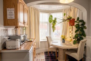 A kitchen with wooden cabinets, a toaster, a sink, and a window with curtains. - Fireside South Shore flat · steps from the beach and the Big One (Blackpool)