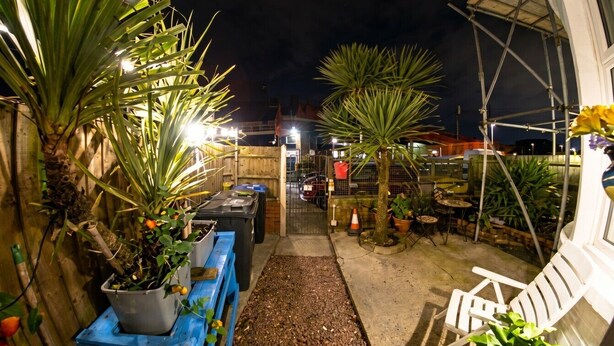 A nighttime outdoor area with potted plants, a pathway, and a white chair. - Fireside South Shore flat · steps from the beach and the Big One (Blackpool)