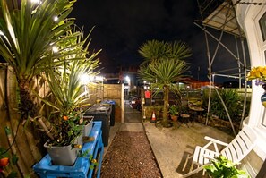 A nighttime outdoor area with potted plants, a pathway, and a white chair. - Fireside South Shore flat · steps from the beach and the Big One (Blackpool)