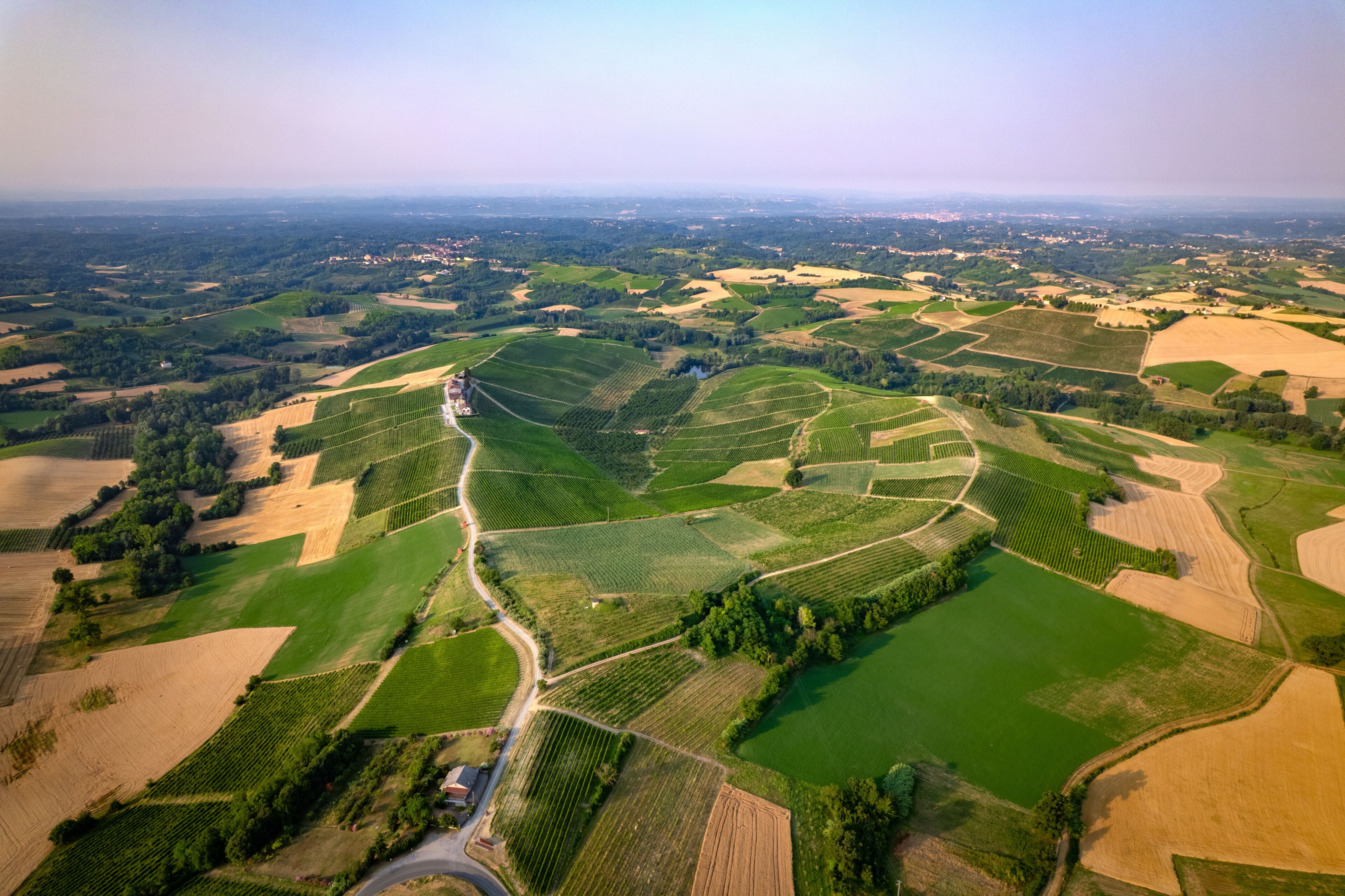 Vista aérea de un paisaje rural con campos en terrazas, un camino sinuoso y un edificio pequeño.