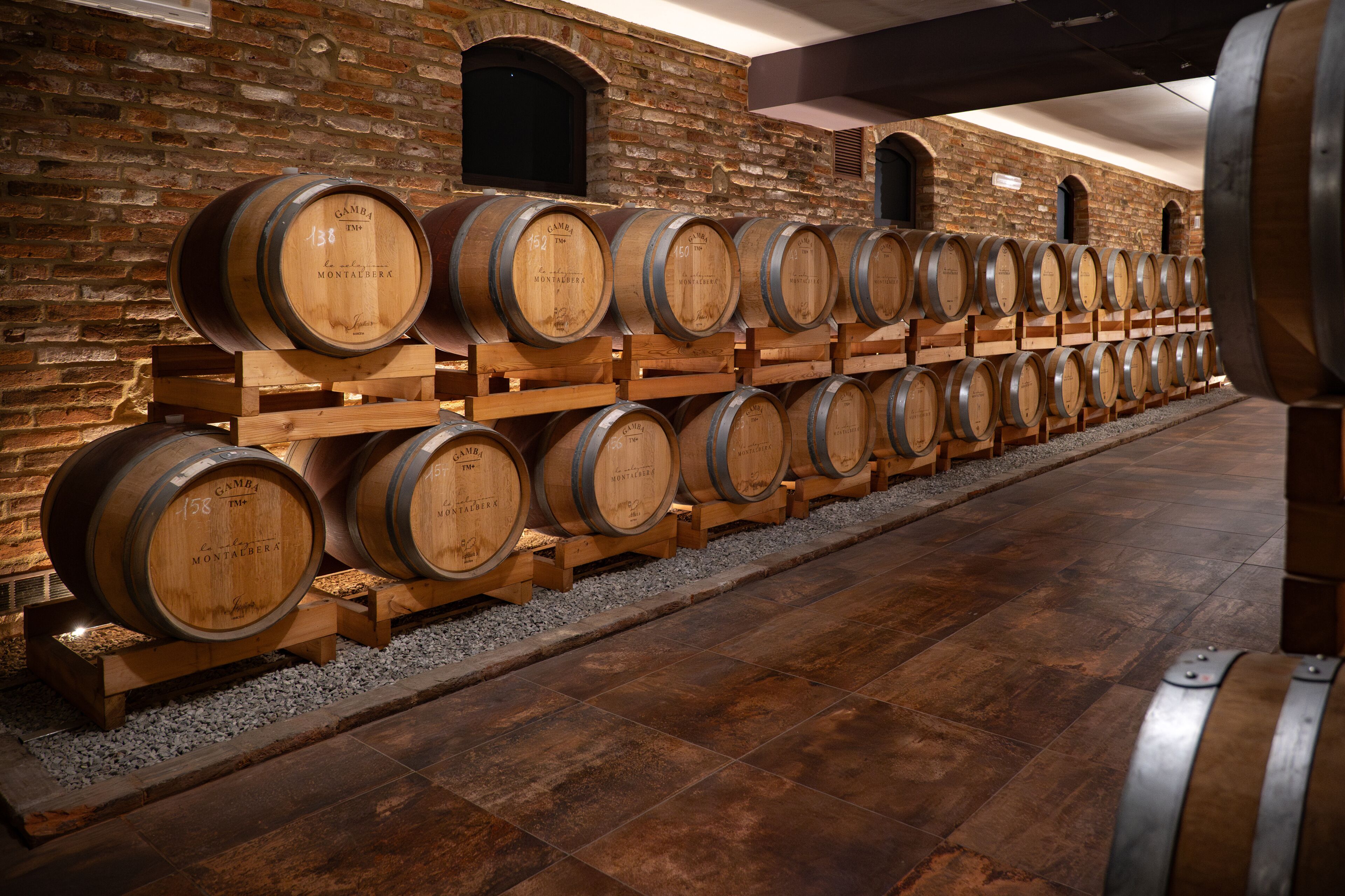 Des barriques en bois, alignées en rangées contre un mur de briques.