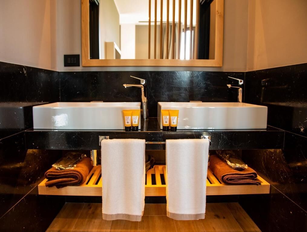 A bathroom with two sinks, a mirror, and towels on wooden shelves.