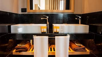 A bathroom with two sinks, a mirror, and towels on wooden shelves.