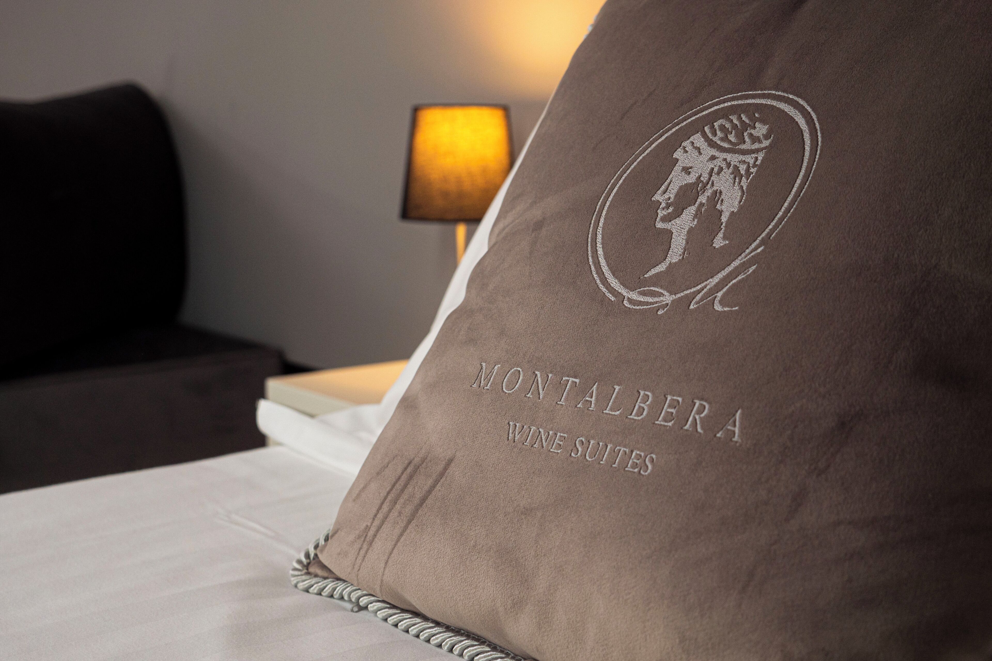 Un coussin orné en relief du logo « Montalbera Wine Suites ».
