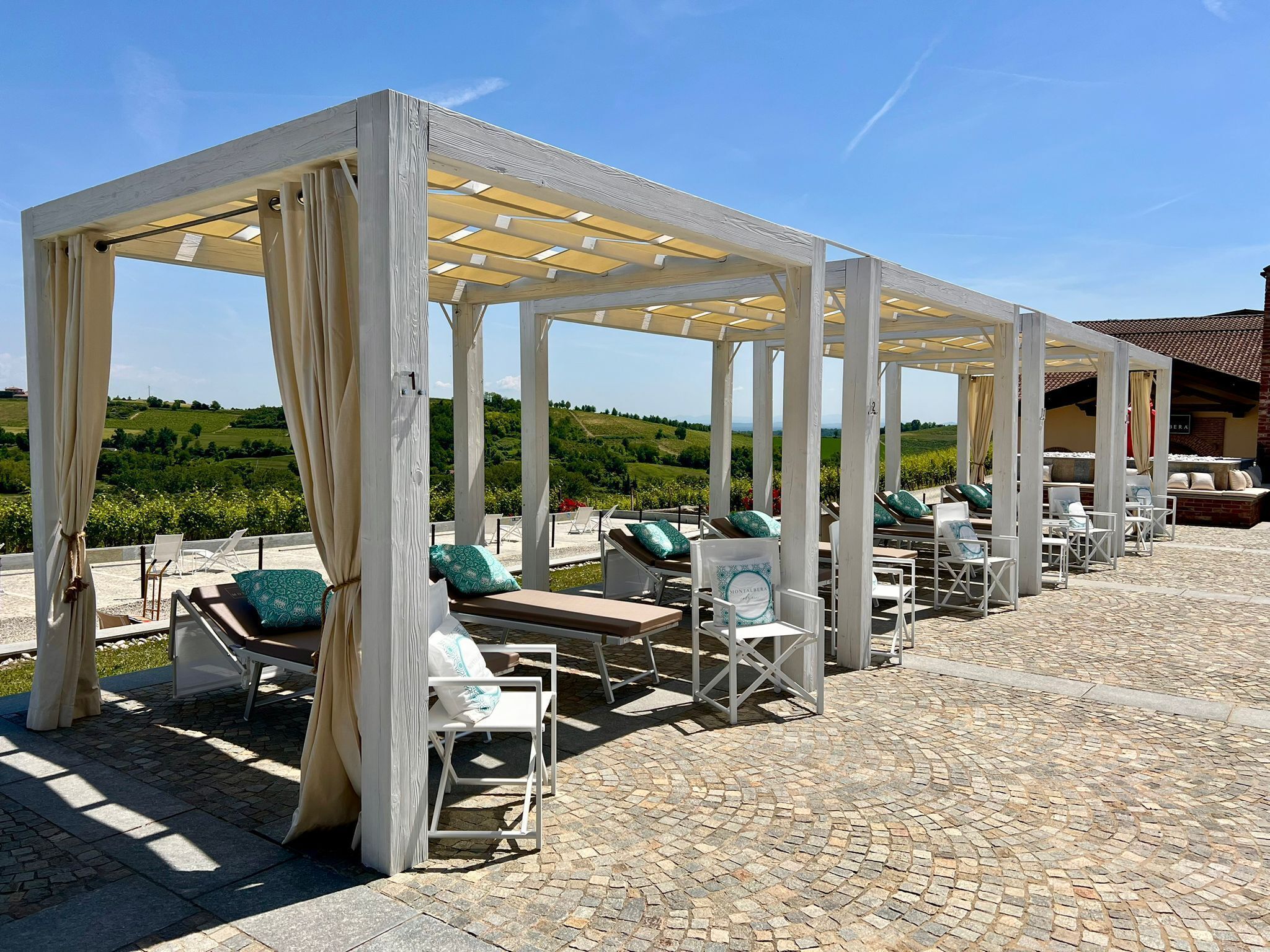 Un espacio de estar al aire libre con sillones reclinables y una estructura de pérgola.