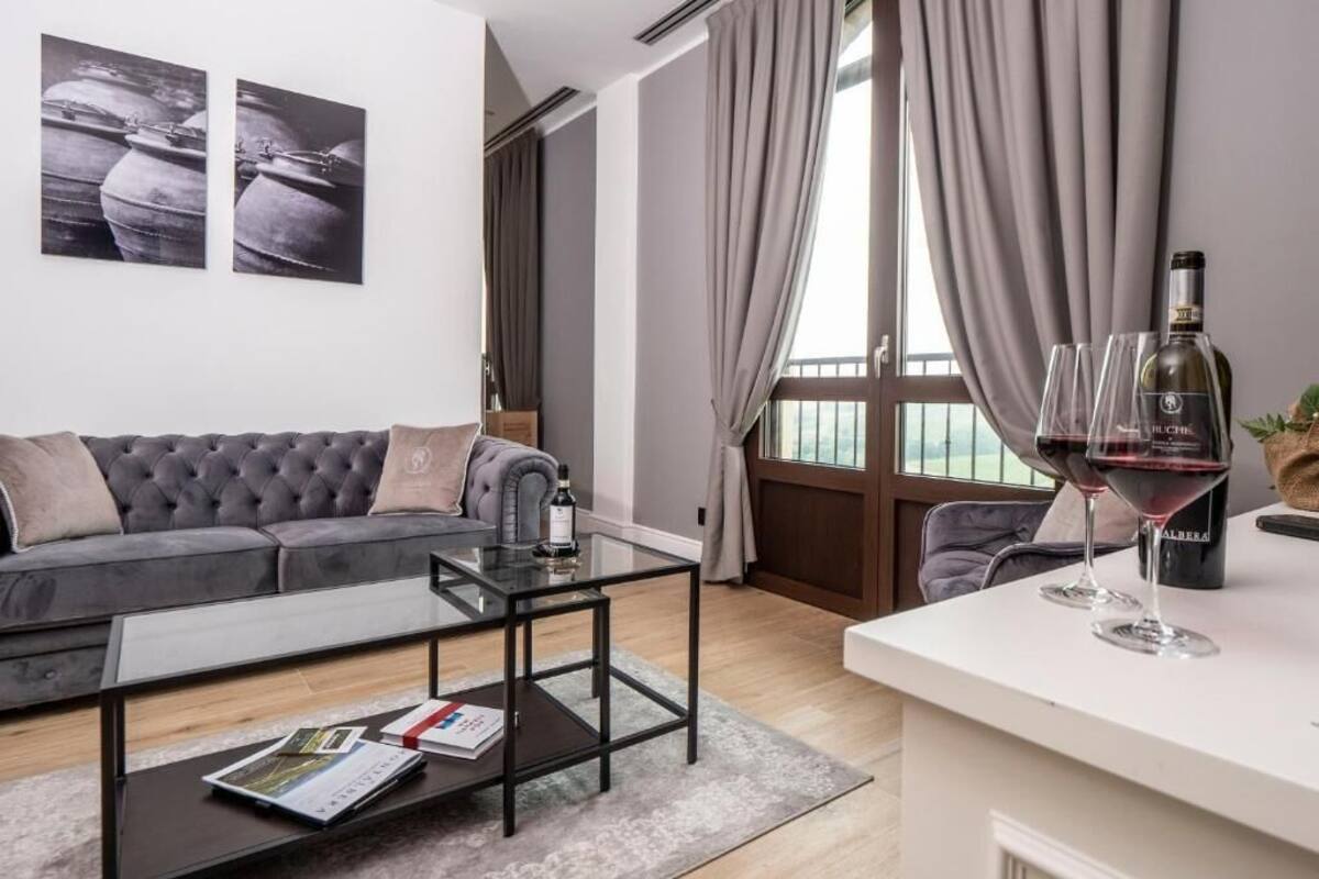 Ein modernes Wohnzimmer mit einer Couch, einem Glastisch und Blick ins Freie durch große Fenster.