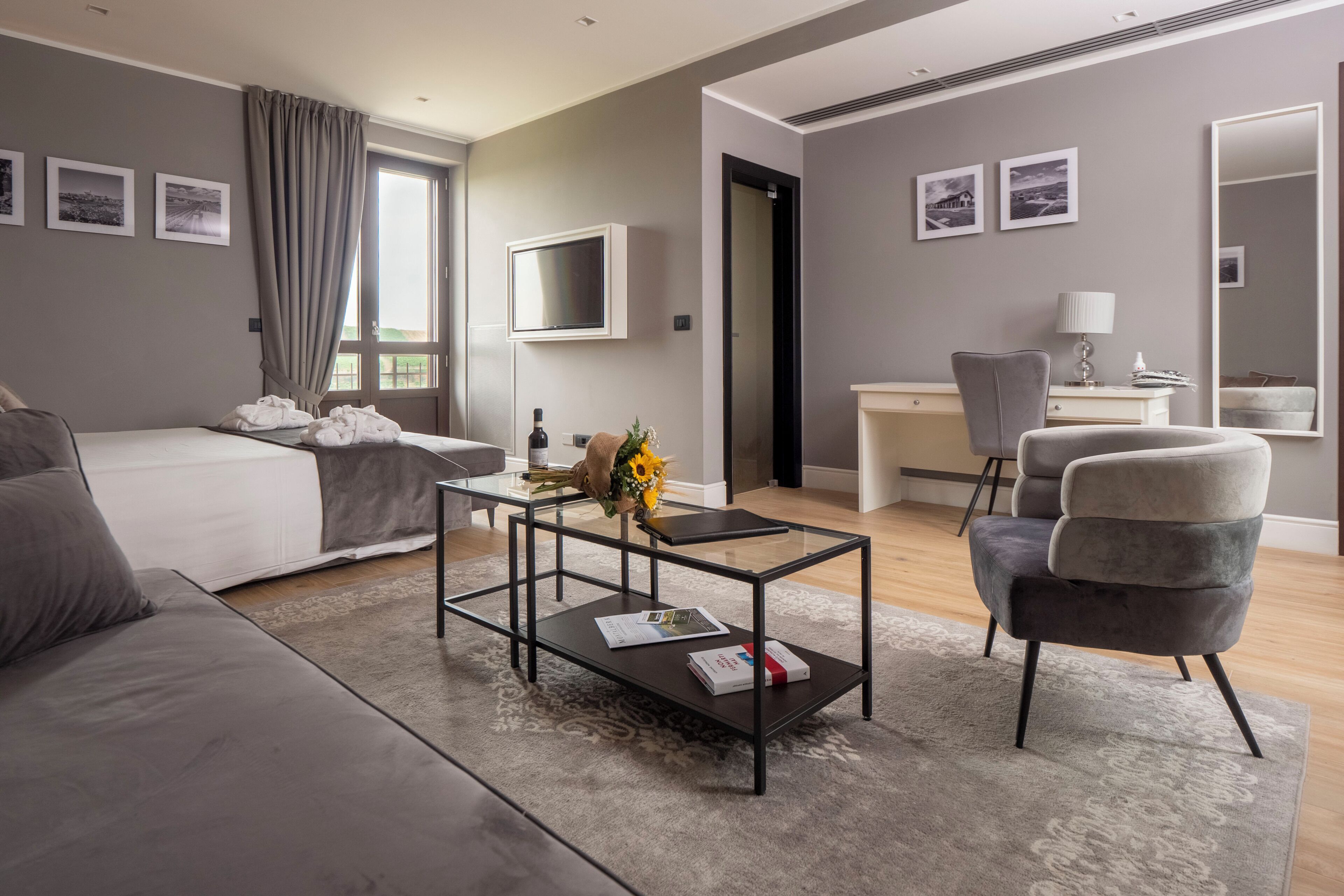 Una habitación de hotel moderna con cama, escritorio, silla, mesa de centro y televisión.