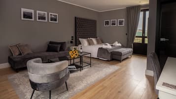 Una habitación de hotel moderna con una cama grande, un sofá, una silla y una mesita con un jarrón de girasoles.