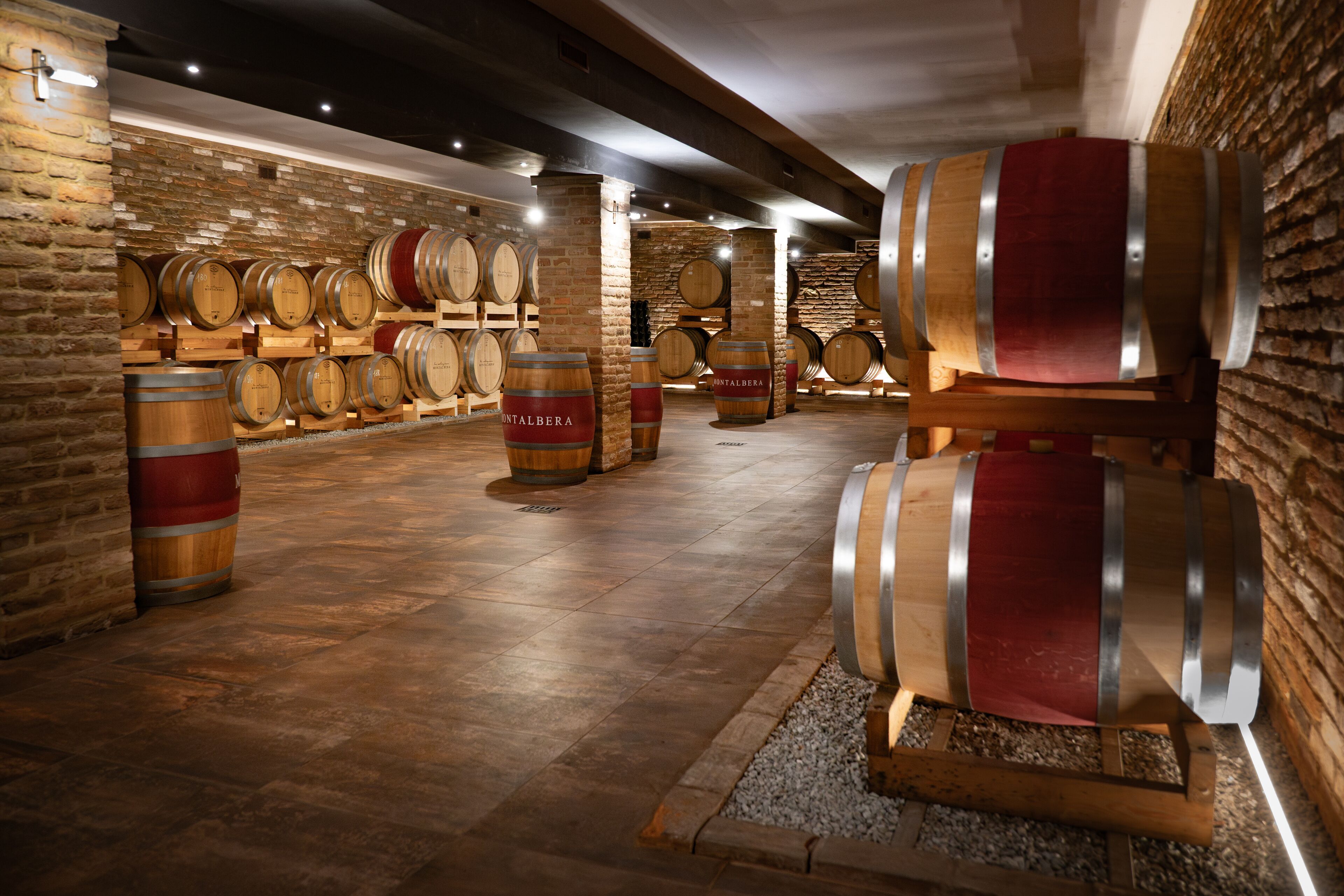 A wine cellar with wooden barrels arranged against brick walls and a polished floor.