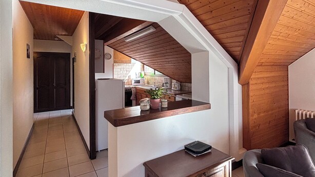 Une cuisine avec des poutres en bois au plafond, un plan de travail et une chaise.