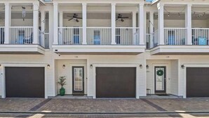 A row of two-story townhouses with balconies, garage doors, and a clear sky. - Crystal Beach Townhome | Golf Cart & Bikes | Pool View | Walk to Beach & Destin Commons (Destin)