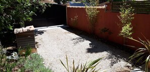 A gravel courtyard with a black gate, a red wall, and some greenery. - Cap Anguilla, guest room near Cassis (Carnoux-en-Provence)