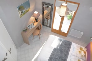 A bathroom with a bathtub, a mirror, a desk with a chair, and a hanging light fixture. - Cap Anguilla, guest room near Cassis (Carnoux-en-Provence)