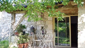 Un edificio de piedra con un patio, asientos al aire libre y un farol.