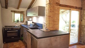 Una cocina con estufa a gas, microondas, pileta y ventana con vista a un patio.