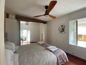 A bedroom with a bed, a ceiling fan, a window, and a door leading to a balcony. - ElegAnse, spacious house, near Lyon (Anse)
