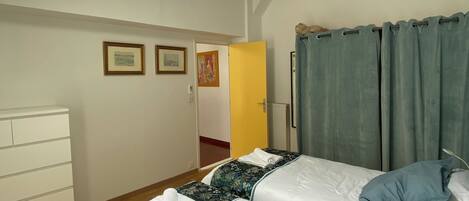 Ein Schlafzimmer mit zwei Betten, einem Deckenventilator, einem Oberlicht, einer Holzkombination und einer Tür zu einem weiteren Raum.