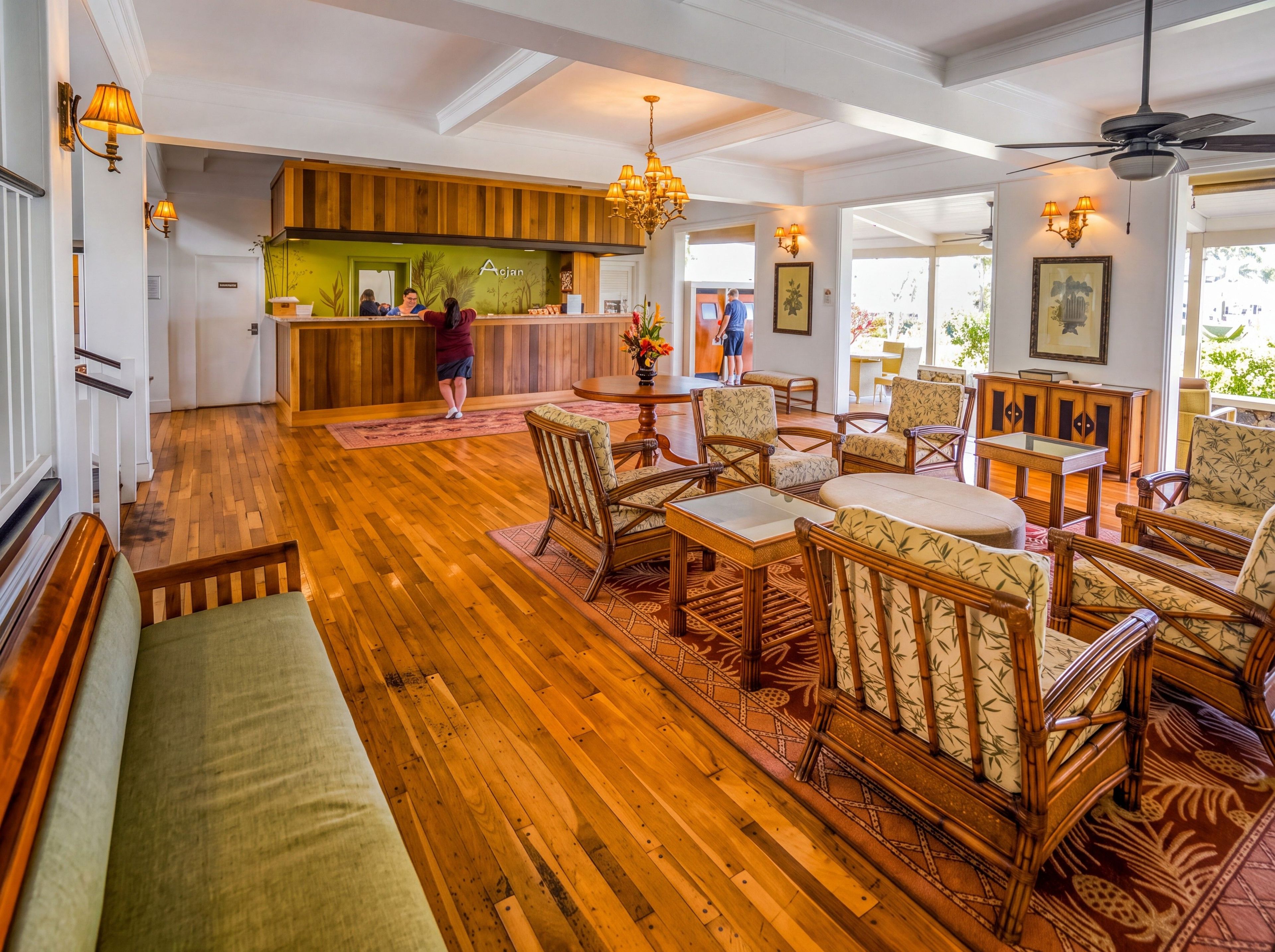 A lobby with wooden flooring, wicker furniture, and a reception desk.