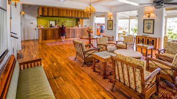 A lobby with wooden flooring, wicker furniture, and a reception desk.