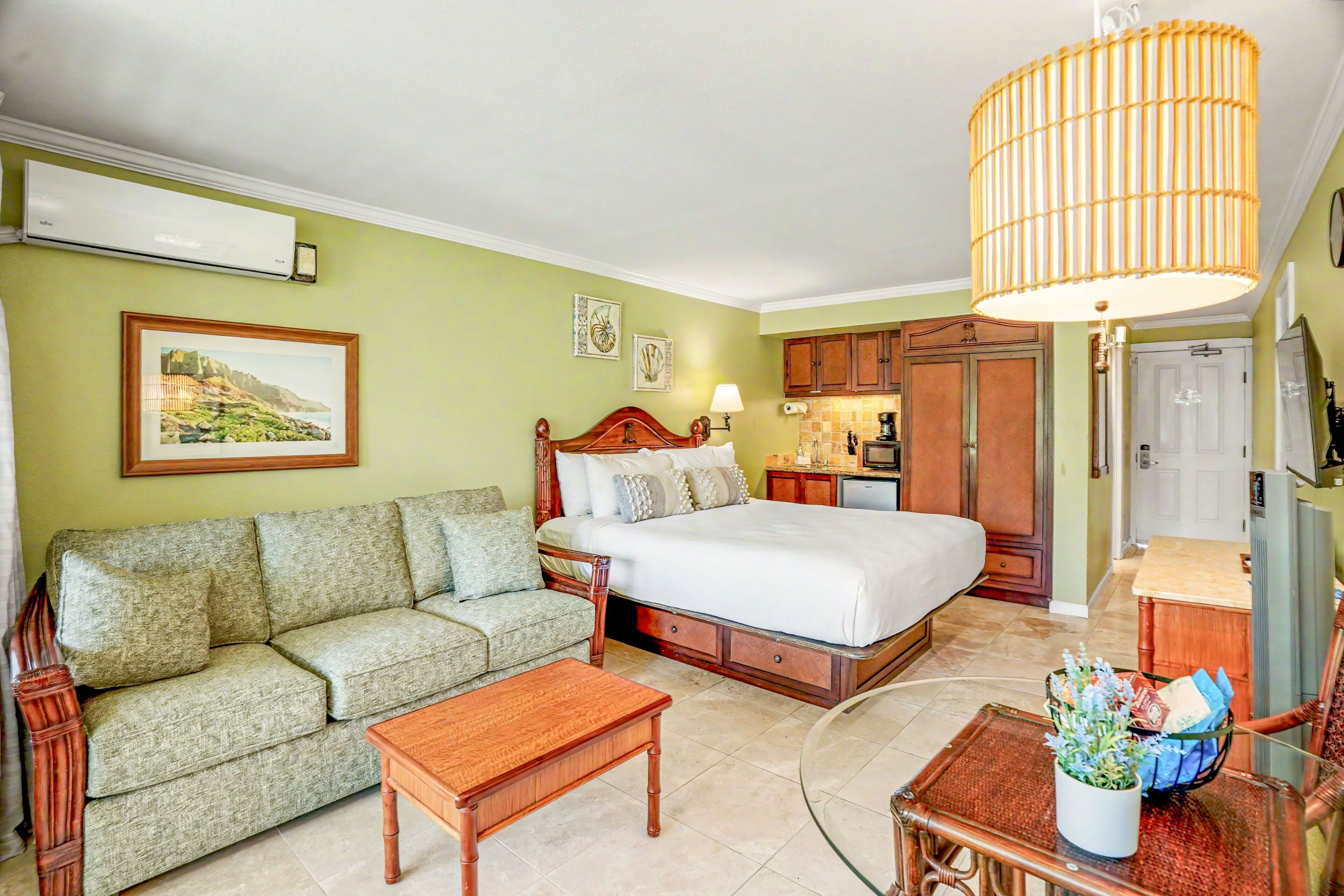 A bedroom with a bed, a sofa, a coffee table, and a dining area with a table and chairs.