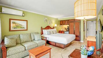 A bedroom with a bed, a sofa, a coffee table, and a dining area with a table and chairs.