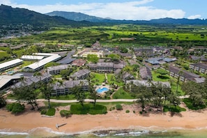 Vue aérienne d’un complexe hôtelier comprenant plusieurs bâtiments, une piscine et une plage.