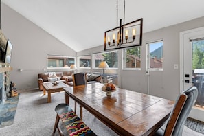 Ein modernes Wohnzimmer mit Essbereich, großen Fenstern und einem Kamin.
