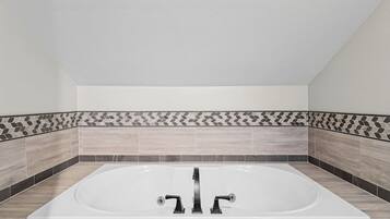 A modern bathroom with a freestanding bathtub, tiled walls, and a neutral color scheme.