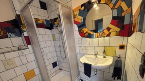 A bathroom with a shower, toilet, sink, and a mirror.