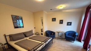 A room with a bed, two chairs, a small table, and a mirror.