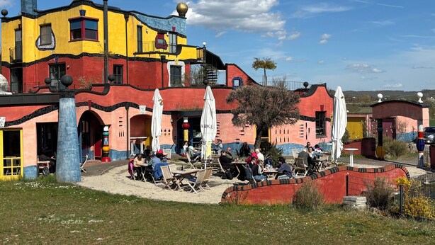 A colorful building with outdoor seating and a tree in front.