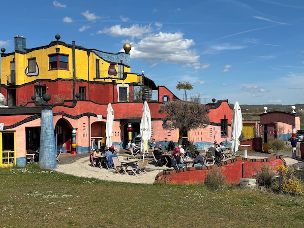 A colorful building with outdoor seating and a tree in front.