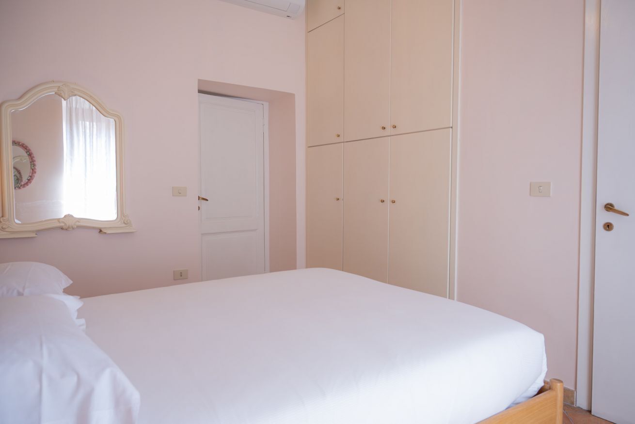 A bedroom with a single bed, a wardrobe, a mirror, and a door.