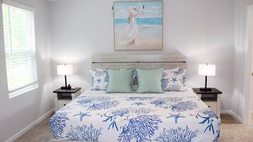 A bedroom with a bed, two bedside tables, a nightstand, a painting, and a window.