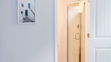 A white door with a glass panel, a white wall, and a framed picture of a blue door and stairs.