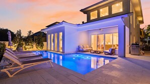 Et moderne hus med swimmingpool, liggestole og grillområde.