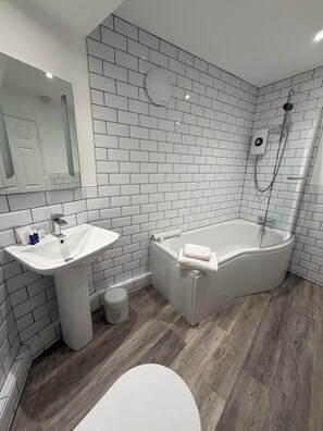 Une salle de bain moderne avec des carreaux de métro blancs, un lavabo blanc, une baignoire et une douche.