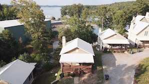 A residential area with houses, a gravel driveway, and a body of water in the background.
