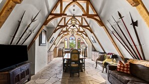 Ein großzügiges Loft mit einer gewölbten Decke, Steinböden, einem Essbereich und einer gemütlichen Sitzecke mit Fernseher.