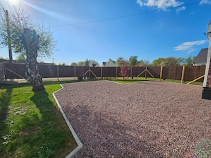 A gravel driveway leading to a house with a fenced yard.