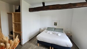 Une chambre à coucher avec un lit, des étagères en bois, une petite table et un tableau accroché au mur.