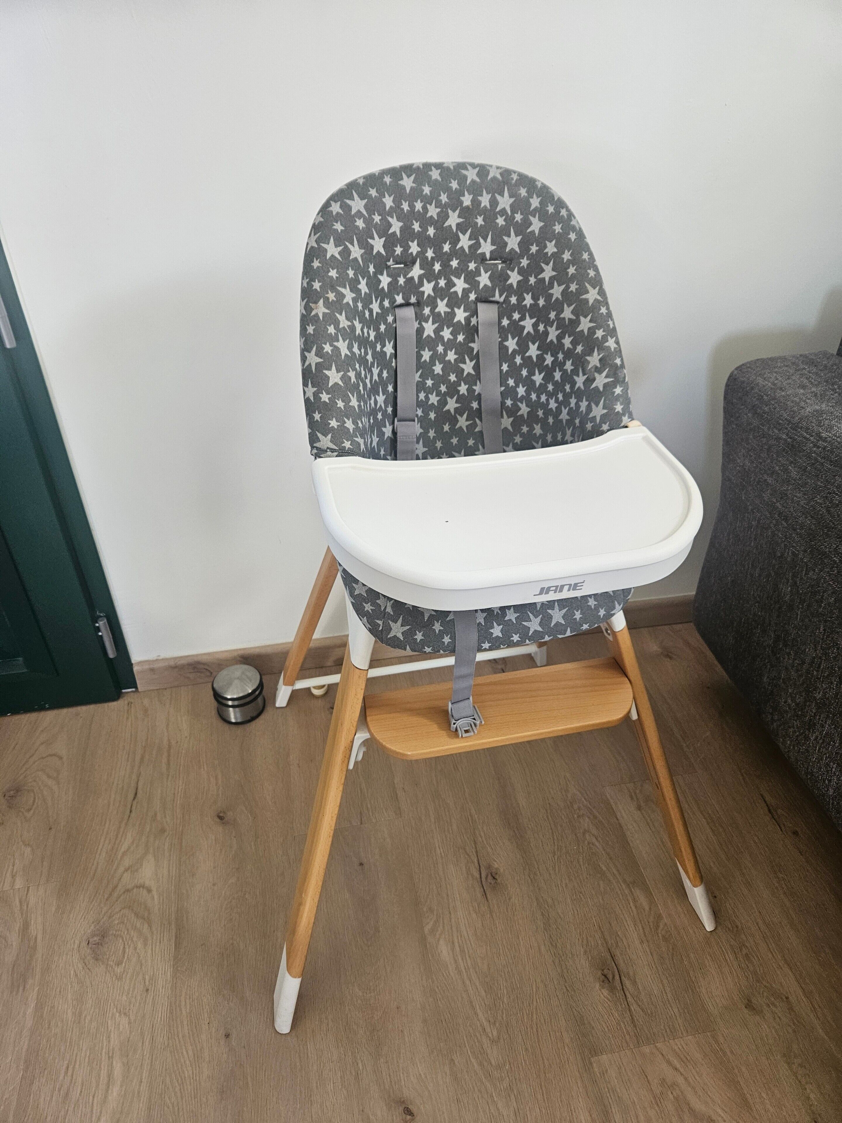 A high chair with a star pattern, a white tray, and wooden legs.